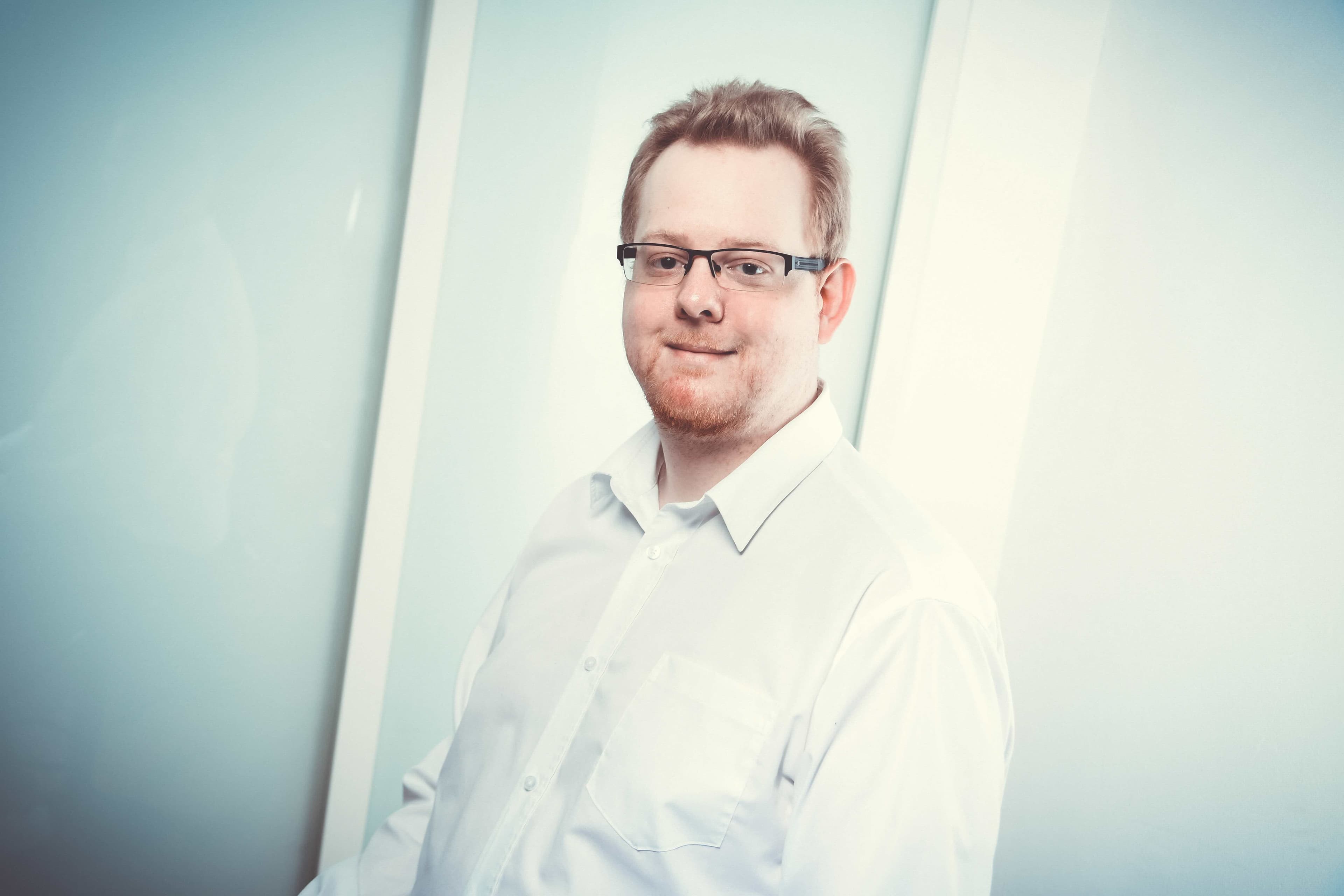 Jörg Amelunxen lehnt lässig an einem Tisch, authentisches Porträt